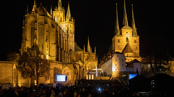 Der Erfurter Dom erstrahlt erleuchtet anlässlich des Martinifestes am 11.November. Im Dunkeln erkennt man mehrere Personen, die auf eine Bildschirm mit Lyrics zum Mitsingen schauen.