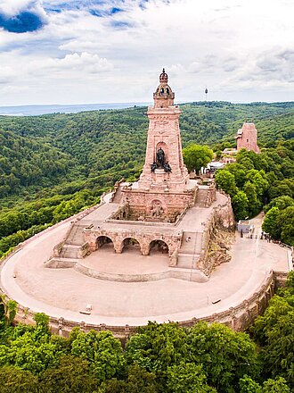 Das Kyffhäuser Barbarossadenkmal aus rotem Sandstein erhebt sich auf einer bewaldeten Hügelkuppe