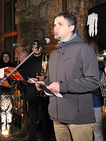 Ein Mann steht mit einem Zettel am Mikrofon und hält eine Ansprache. Im Hintergrund sieht man eine Musikband für die Martinsfeierlichkeiten in Nordhausen