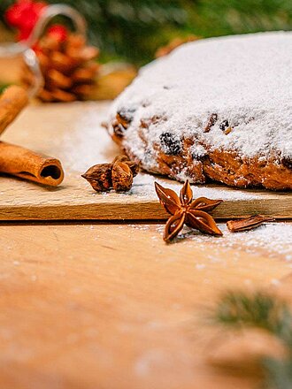 Stollen mit Puderzucker dekoriert mit Tannenzweigen und Zimtstangen