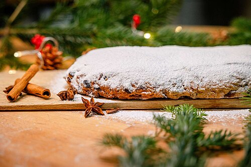 Stollen mit Puderzucker dekoriert mit Tannenzweigen und Zimtstangen