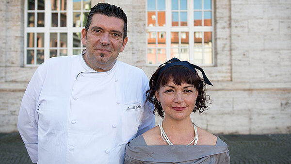 Marcello Fabbri und Doreen Bergmann stehen nebeneinander vor einem historischen Gebäude
