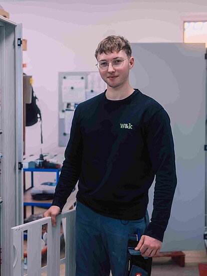 Ein junger Elektroniker steht vor einem Schaltschrank mit elektronischen Komponenten einer verfahrenstechnischen Anlage