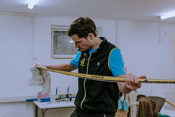 Ein Ingenieur hält mit beden Händen einen Germina-Ski in der Werkstatt