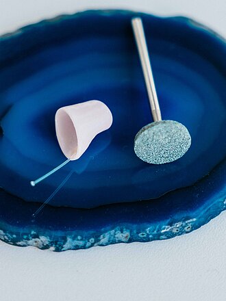 Zwei Otoplastiken auf einer dunkelblauen Achatscheibe auf hellem Untergrund