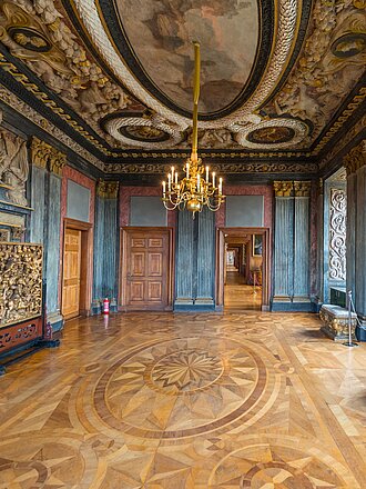 In blau gehaltener Saal mit edlem hölzernen Parkettfußboden und Kronleuchter