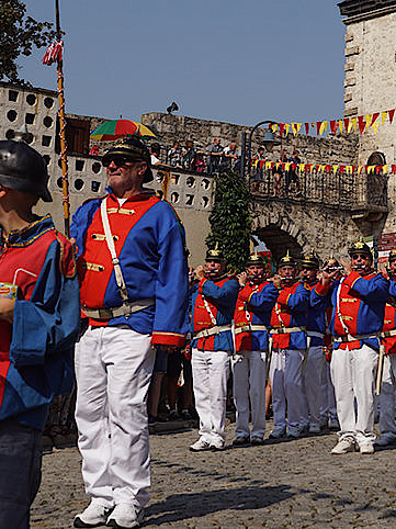 Eine Blaskapelle präsentiert sich in Tracht mit weißen Hosen und blau-roten Jacken bei einem Festumzug in Mühlhausen.