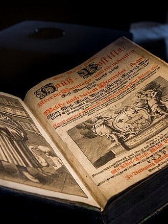 Deckblatt einer Hauspostille aus dem Jahre 1601 mit einem Kupferstich Martin Luthers auf der linken und dem Titel der Publikation im schwarzen und roten Lettern aus dem Besitz Johann Sebastian Bachs