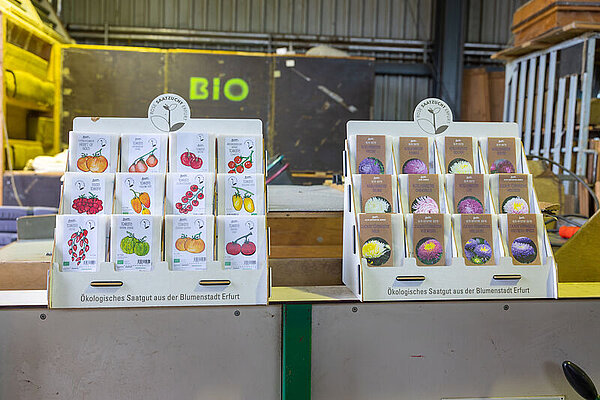 Saatguttüten stehen in zwei Aufstellern in den Hallen von Rose Saatzucht Erfurt