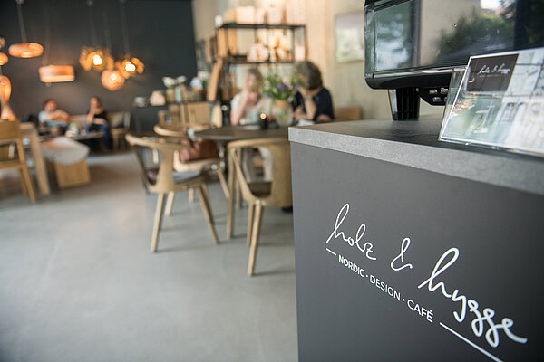 Rattan-Stühle und dunkelgraue Theke im Café „Holz & Hygge“ in Jena