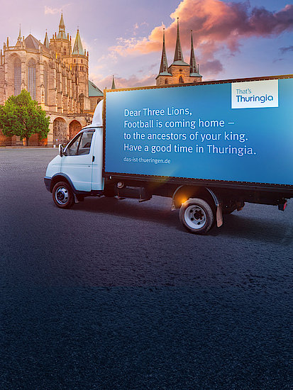 Weiß-blauer LKW mit der Aufschrift: Dear Three Lions, Football is coming home - to the ancestors of your king. Have a good time in Thuringia. steht vor der Altstadt in Thüringen. 