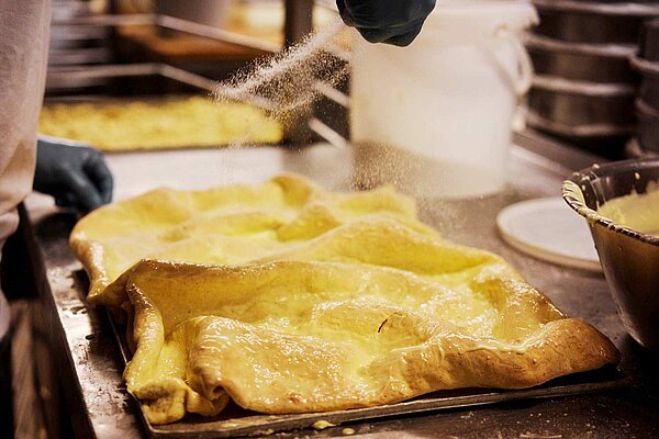 Blechkuchen aus dünner Teigschicht überzogen mit Butter und Puderzucker in einer Backstube