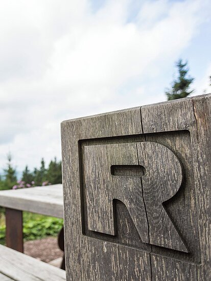 Rastplatz am Rennsteig mit Holzbank, in Holzblock eingraviertem "R" und Ausblick in die Landschaft und in den Horizont