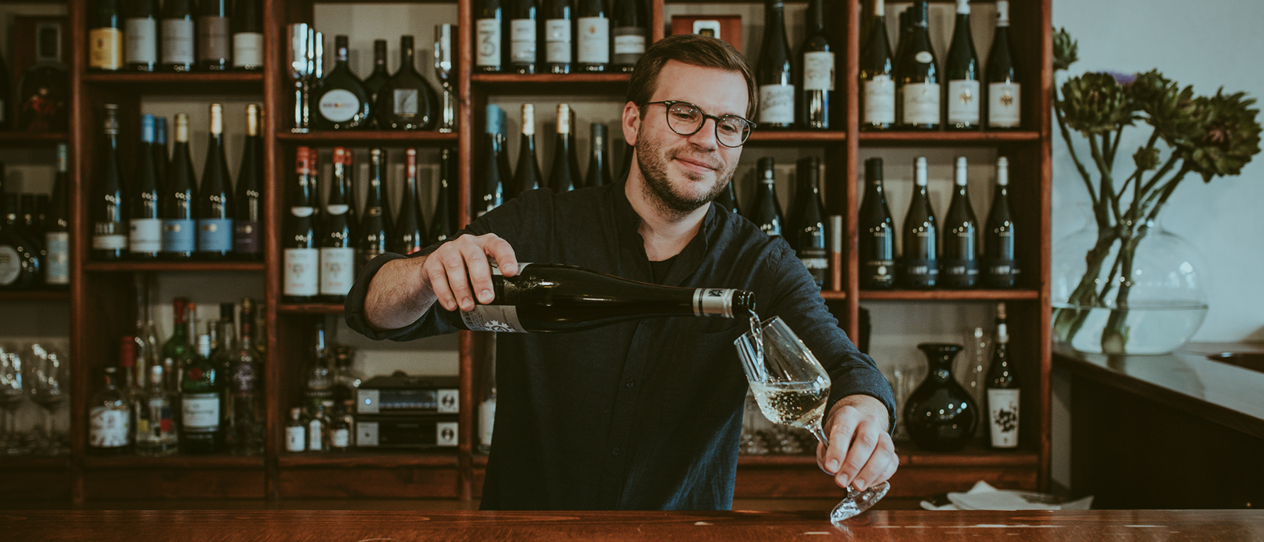 Philip Heine schenkt ein Glas Wein ein.